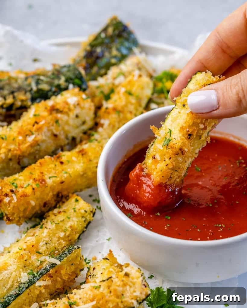 Crispy Air Fryer Zucchini Parmesan Fries 6 air fried zucchini fries being dipped into marinara sauce