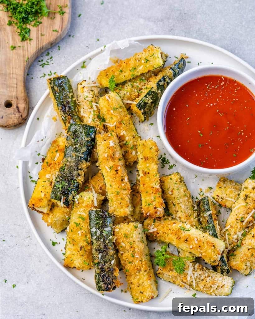 Crispy Air Fryer Zucchini Parmesan Fries 8 top view of zucchini fries on a white plate with red sauce on the side