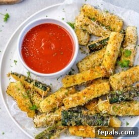 top view zucchini fries on a white plate with a side of ketchup