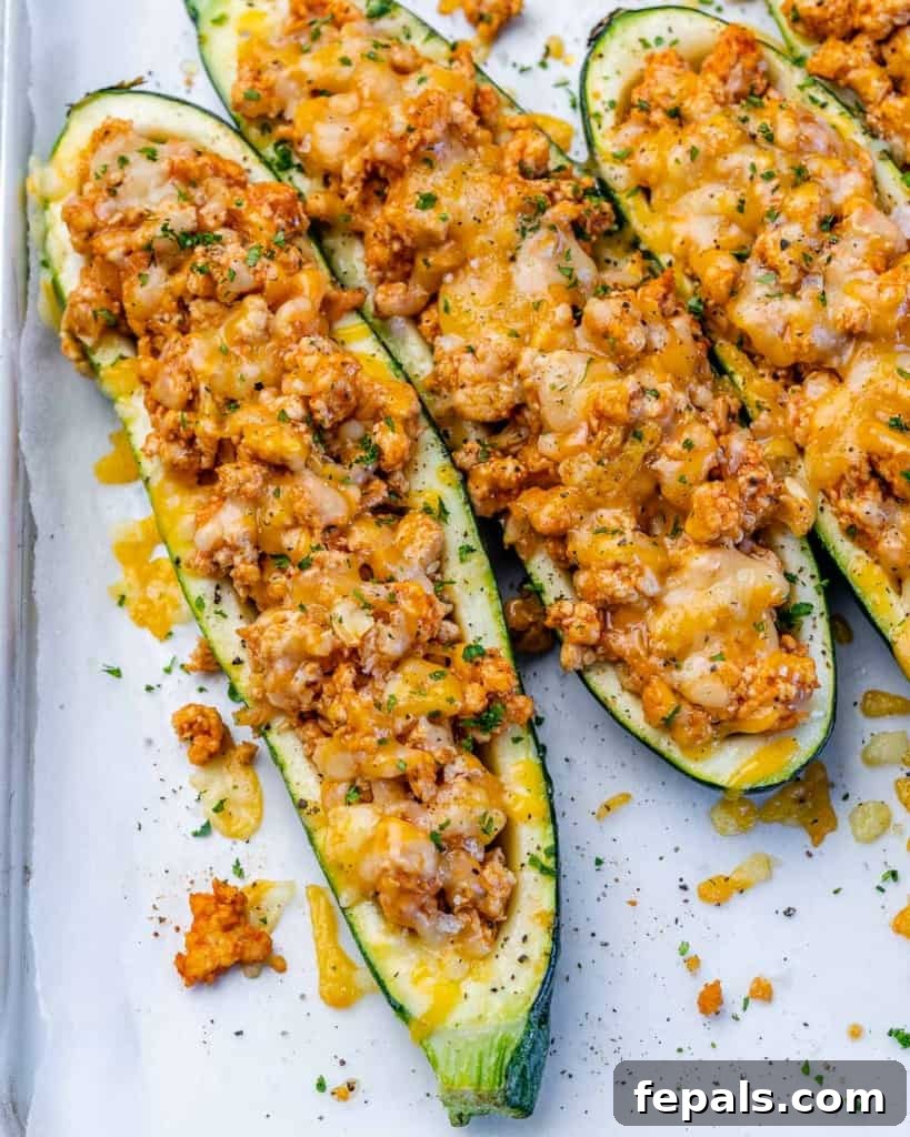 Fiery Buffalo Chicken Zucchini Boats 11 A close-up view of two succulent zucchini boats, perfectly cooked and stuffed with savory buffalo chicken and melted cheese.