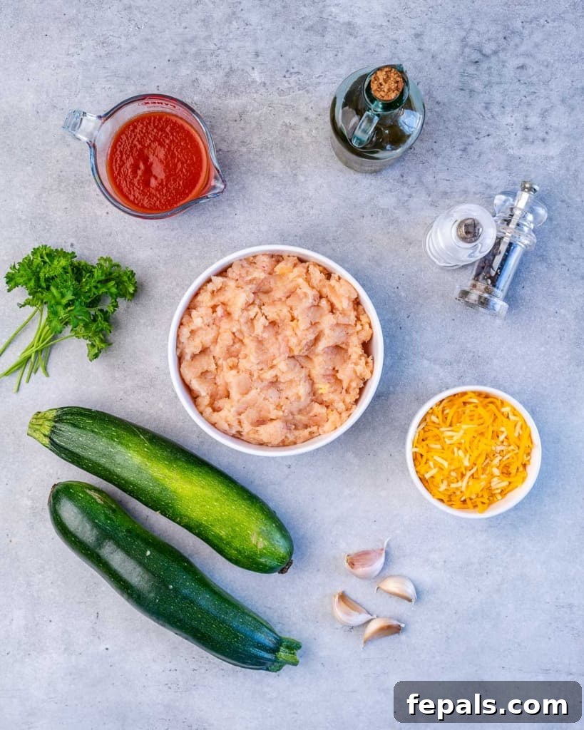 Fiery Buffalo Chicken Zucchini Boats 4 A vibrant display of fresh ingredients laid out, including zucchini, ground chicken, buffalo sauce, garlic, and cheese, ready to be transformed into delicious zucchini boats.