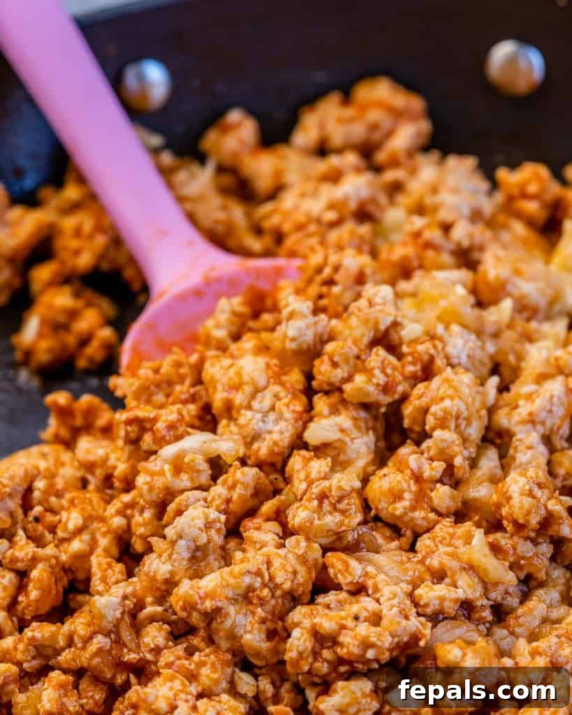 Fiery Buffalo Chicken Zucchini Boats 6 A close-up shot of the savory buffalo chicken stuffing sizzling in a skillet, as it cooks to perfection before filling the zucchini boats.