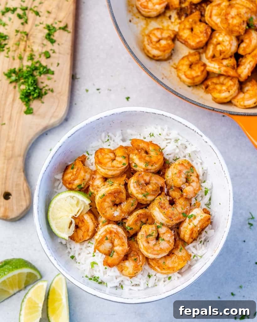 top view bowl of rice topped with cajun shrimp next to a cutting board