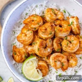 top view of cajun shrimp over a rice of white bowl with a lime wedge for garnish