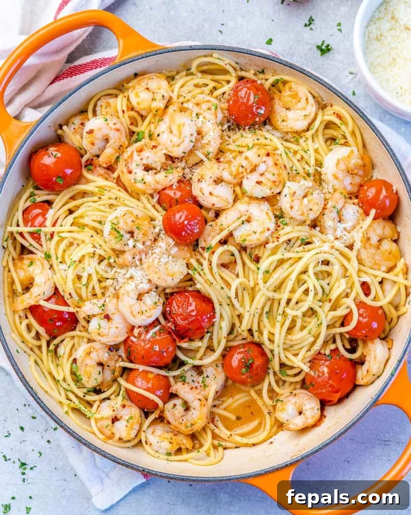 Close-up of garlic shrimp pasta being tossed in a skillet, showing the perfectly coated spaghetti, vibrant tomatoes, and tender shrimp.