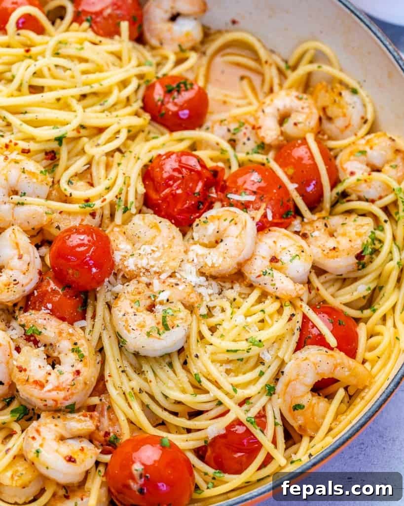 Side shot of a vibrant bowl of garlic shrimp pasta with cherry tomatoes and fresh parsley garnish.