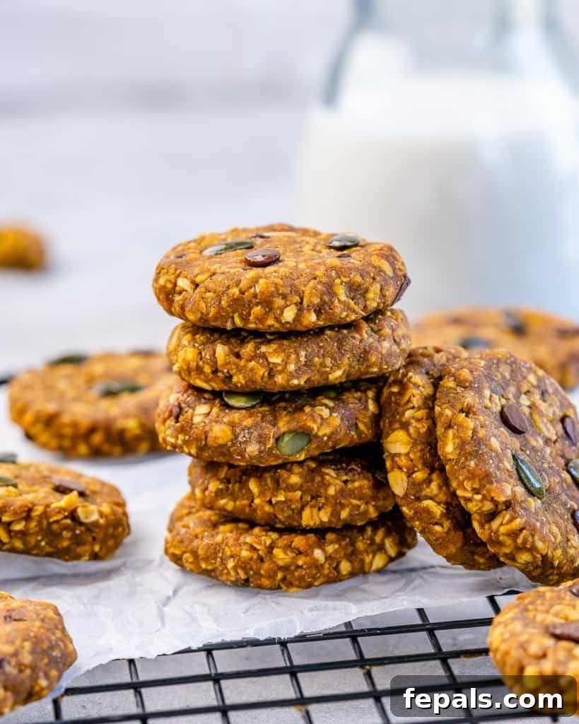 Spiced Pumpkin Oat Delights 2 Stacks of freshly baked pumpkin oatmeal cookies on parchment paper over a wire rack