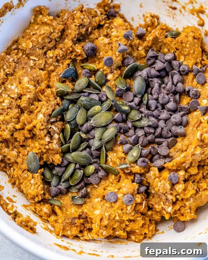 Spiced Pumpkin Oat Delights 6 Raw pumpkin seeds and dark chocolate chips being mixed into the oatmeal cookie batter, enhancing flavor and texture