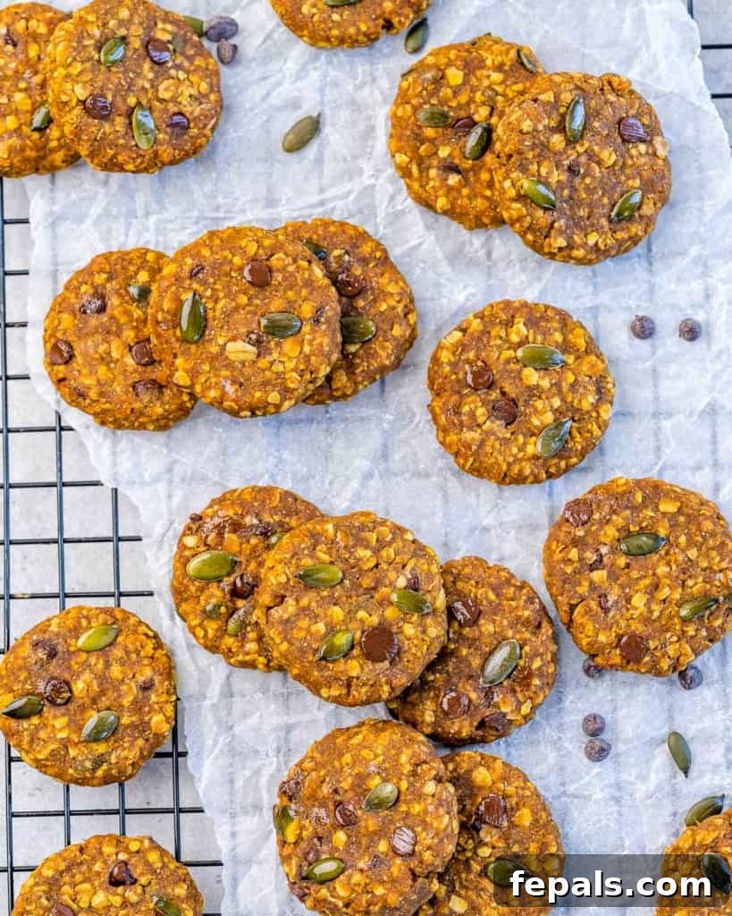 Spiced Pumpkin Oat Delights 7 A cooling rack filled with many freshly baked pumpkin oatmeal cookies on parchment paper, ready to be devoured