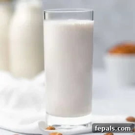 square image of a clear glass cup cup filled with almond milk