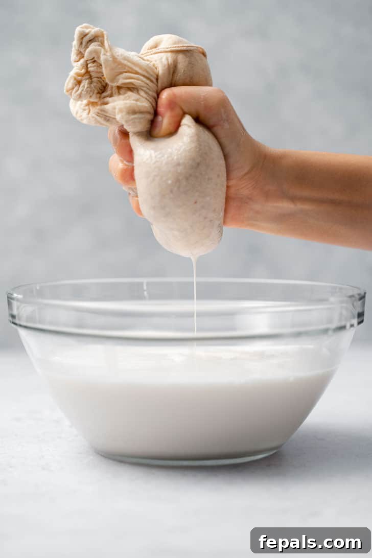 squeezing almond milk with nut milk bag over bowl