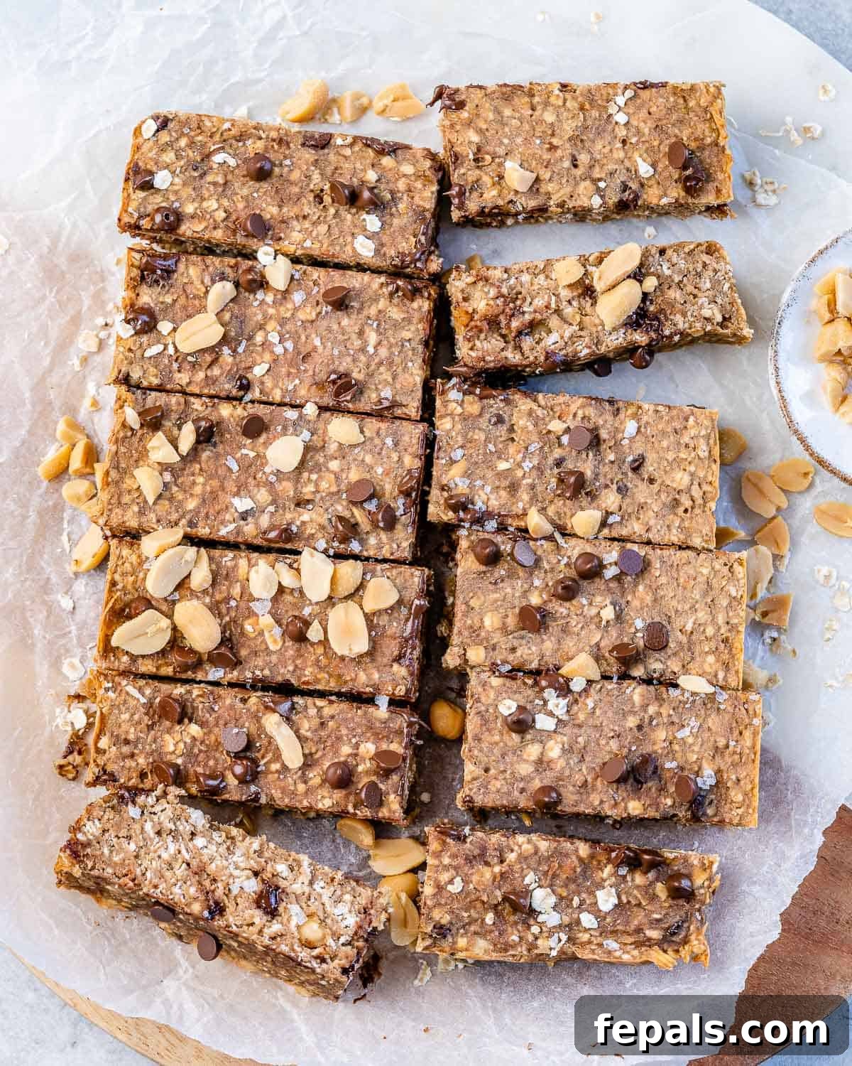 Healthy Peanut Butter Oatmeal Bars Twelve golden brown healthy oatmeal bars, cut into neat slices and topped with chocolate chips and crushed peanuts, arranged on a baking sheet.