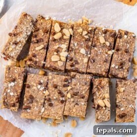Wholesome Oat Energy Bars 5 A single oatmeal bar, topped with crunchy peanuts, resting on parchment paper, highlighting its delicious texture.