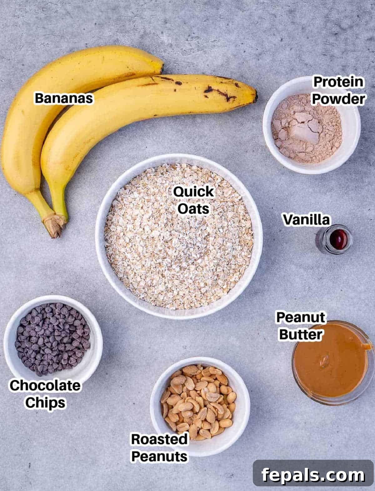 Wholesome Oat Energy Bars 2 A flat lay arrangement of ingredients for healthy oatmeal bars, including ripe bananas, a jar of peanut butter, quick oats, protein powder, chocolate chips, and peanuts.