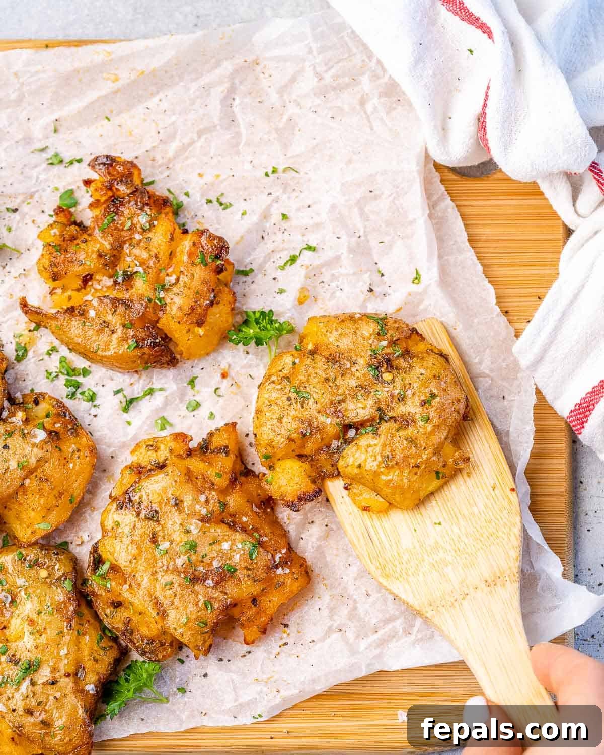 Garlic Smashed Potatoes top view of smashed potatoes with wooden spoon
