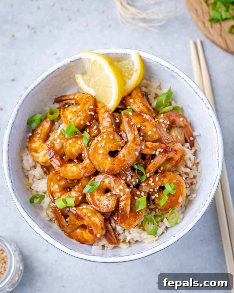 top view shrimp teriyaki over a bowl of white rice with lemon garnishes 