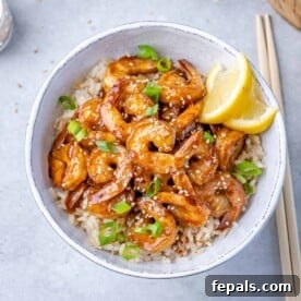 top view teriyaki shrimp over brown rice in a white bowl
