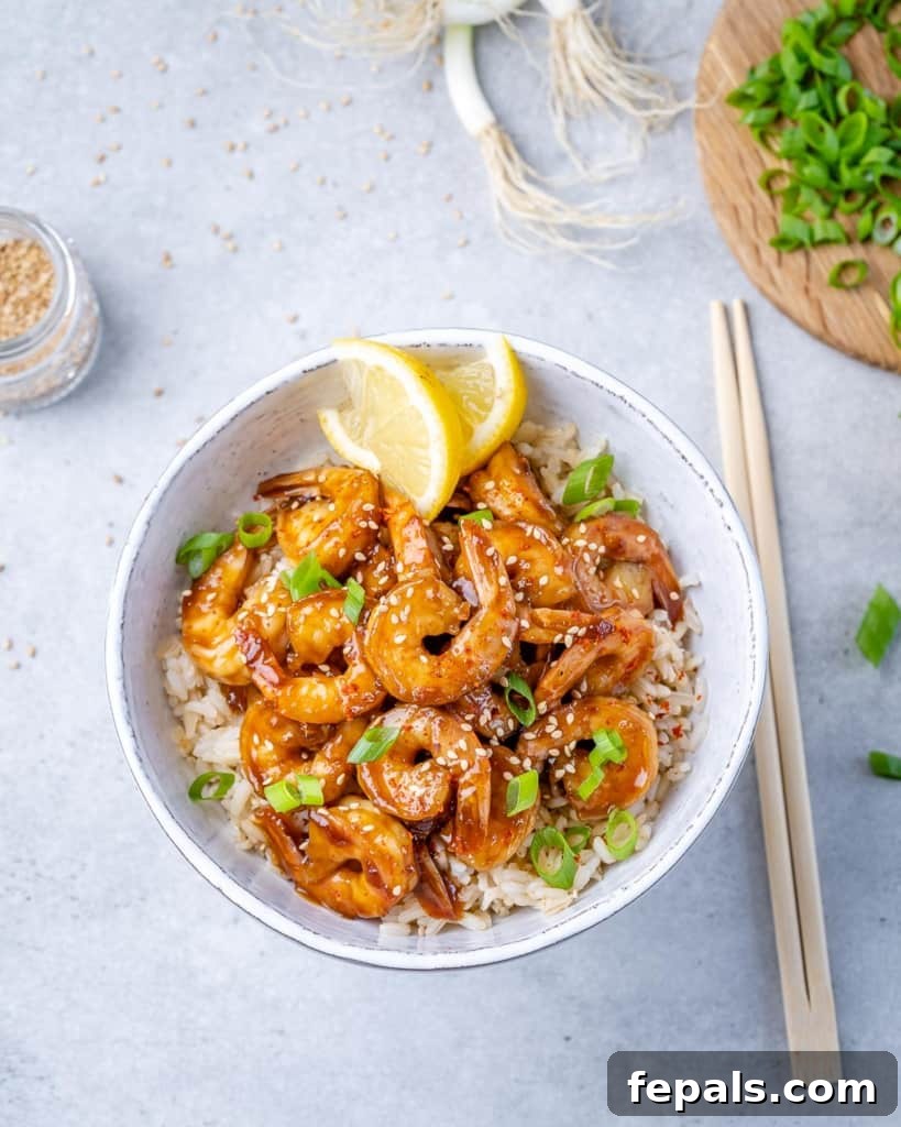 top view of a bowl of shrimp teriyaki with rice and a side of chop sticks