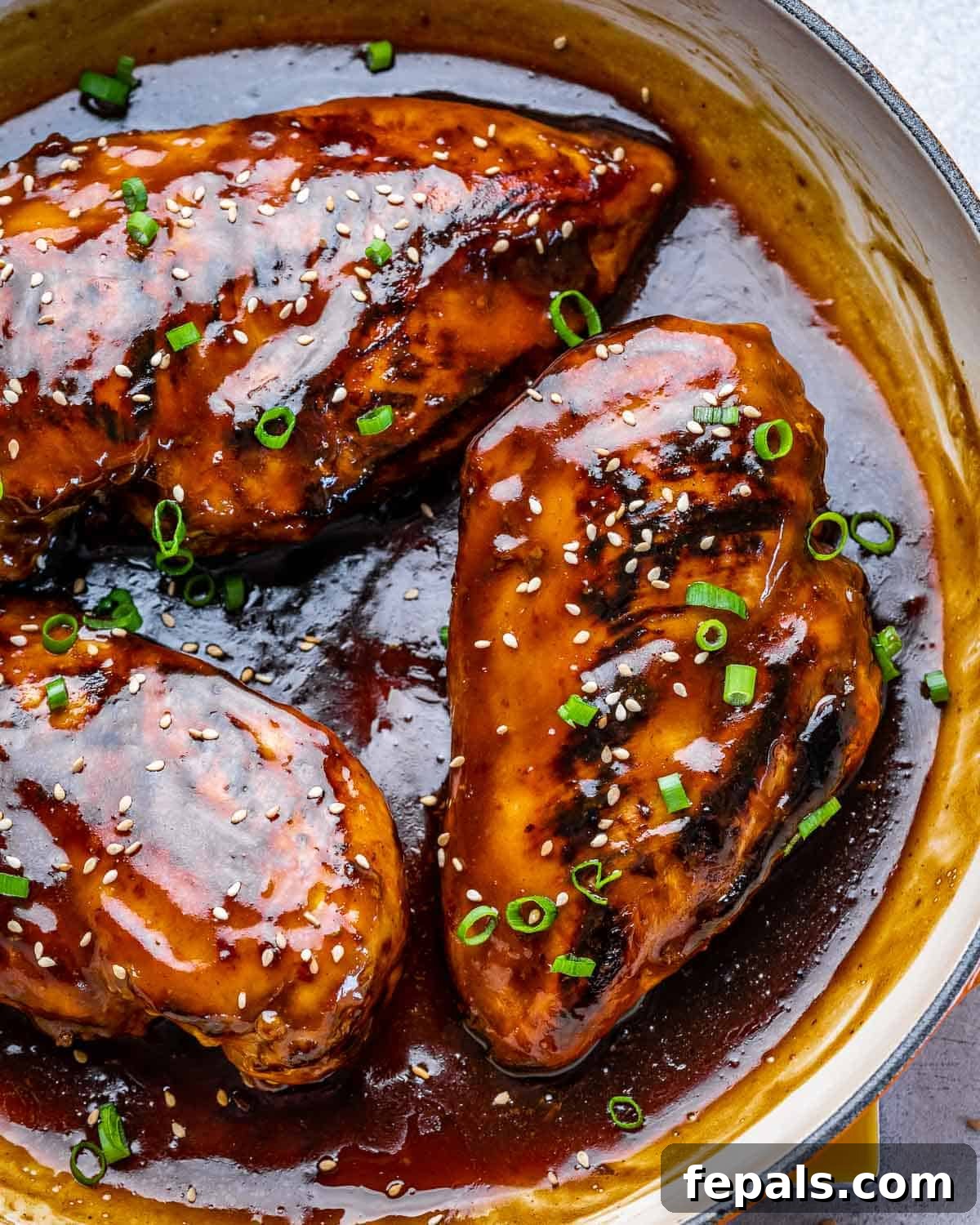 close view of Asian chili chicken breasts in pan with sauce