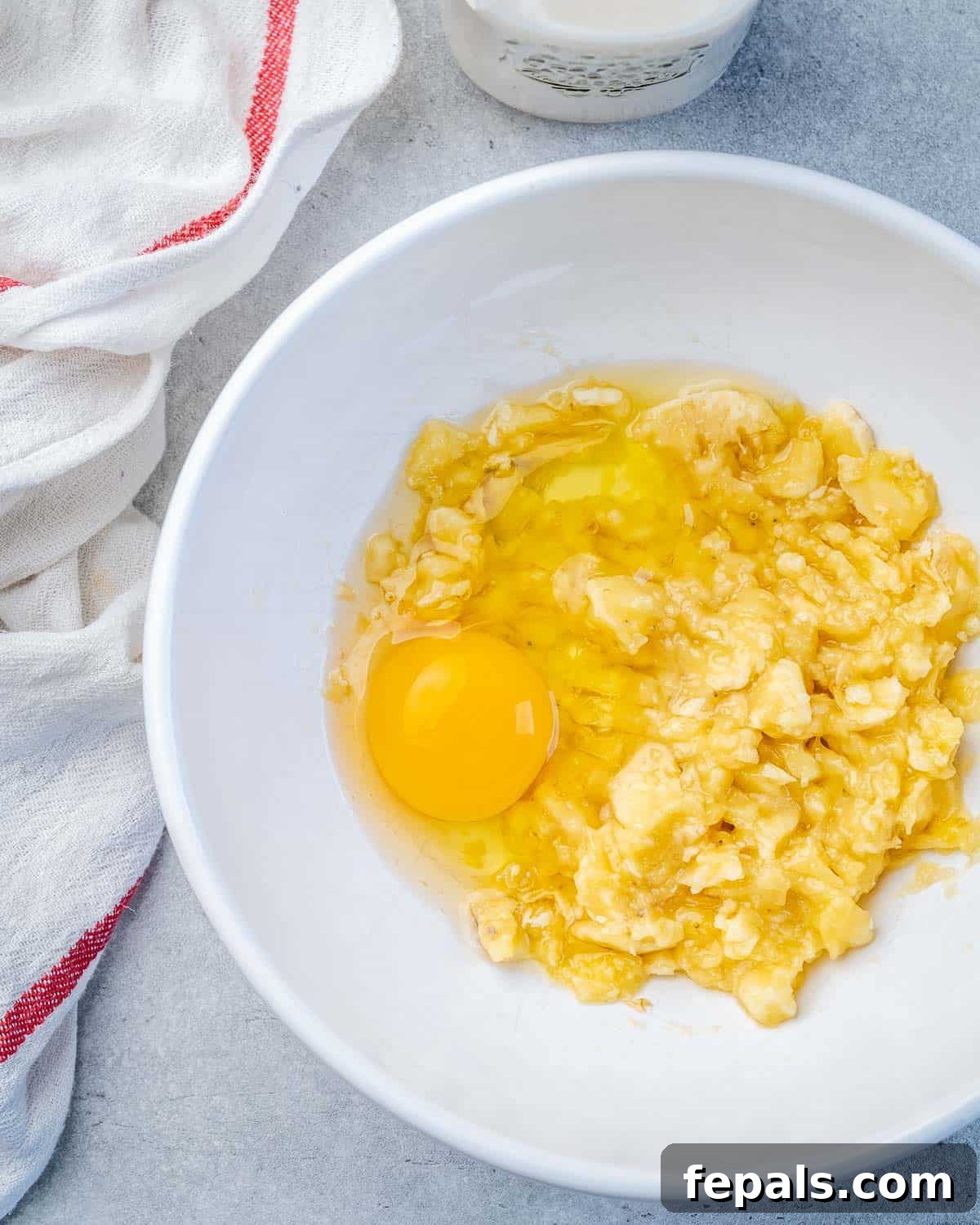 A bowl filled with a mixture of egg and flour, ready for pancake batter preparation, symbolizing the initial steps of the recipe.
