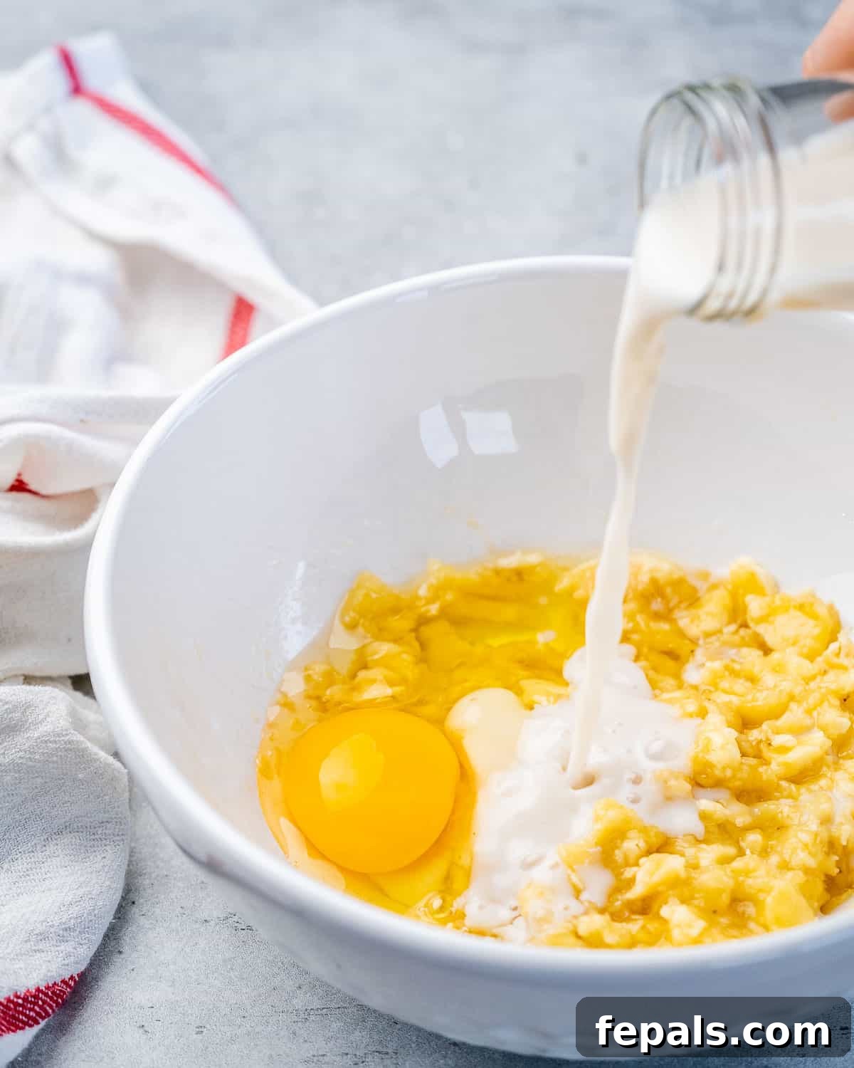 A bowl containing a creamy mixture of egg, flour, and milk, illustrating the combined wet and dry ingredients for a smooth pancake batter.