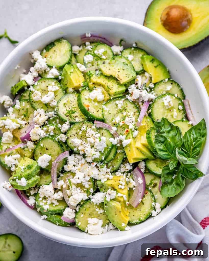 top view of cucumber salad in a white bowl with feta and avocado