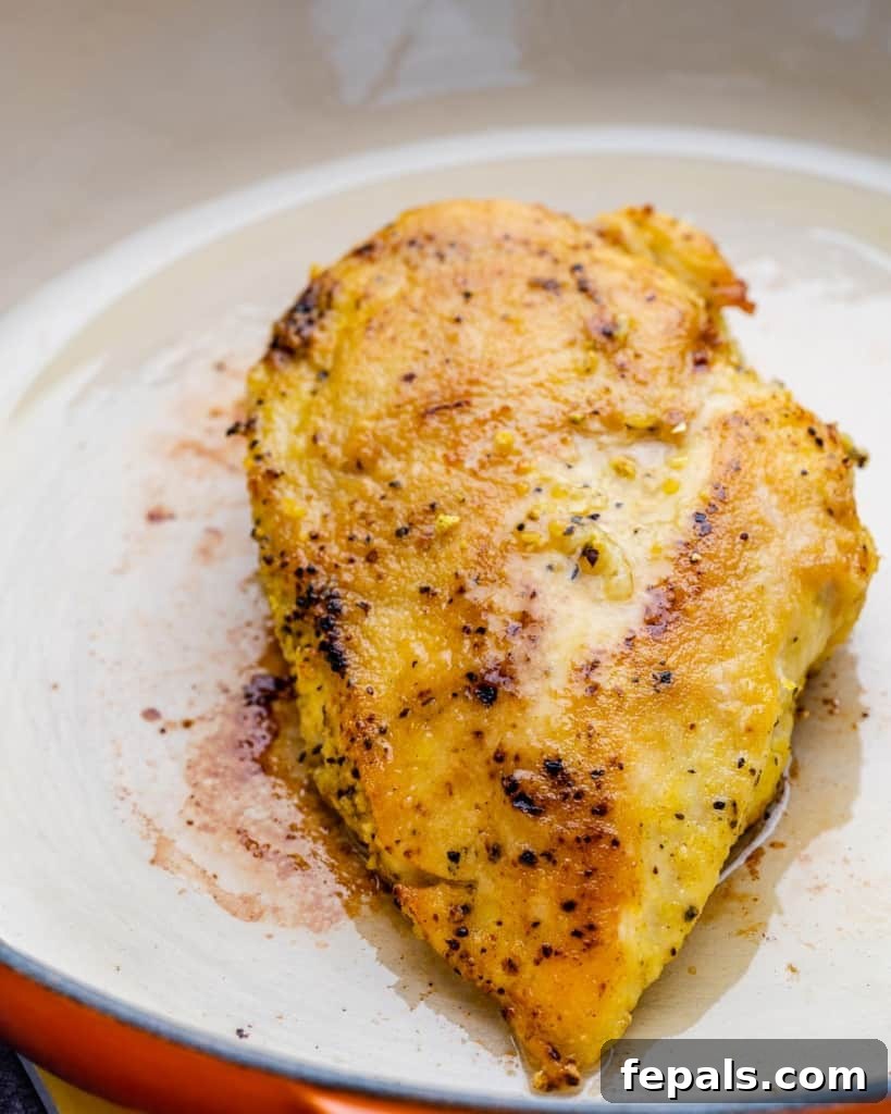 Golden Pan-Seared Lemon Garlic Chicken 5 Golden-brown pan-fried chicken breasts cooking in a skillet, showcasing the perfect sear.