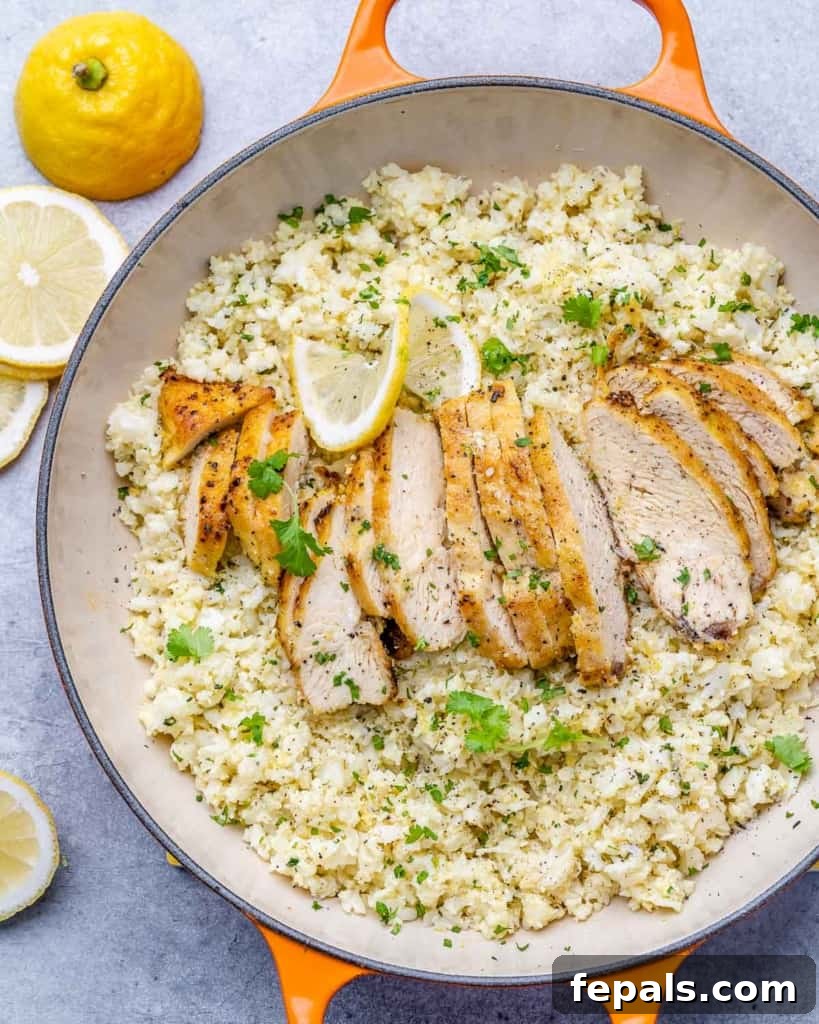 Golden Pan-Seared Lemon Garlic Chicken 7 Top view of a beautifully plated dish of sliced lemon garlic chicken breast served over cauliflower rice, garnished with fresh cilantro and lemon.