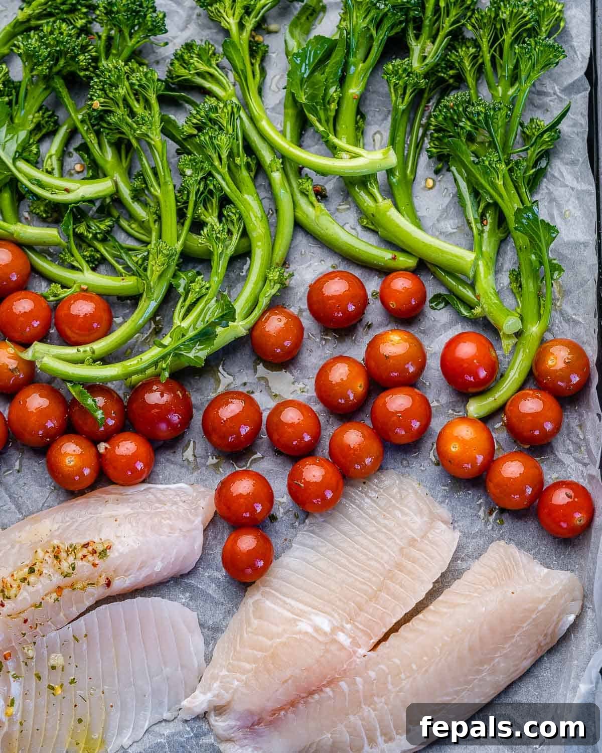 Easy Baked Tilapia in the Oven sheet pan with tilapia fillets, broccolini, and tomatoes
