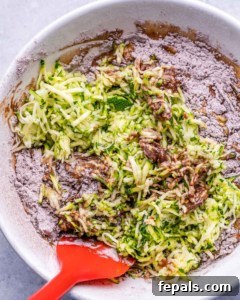zucchini bread batter being mixed with red spatula