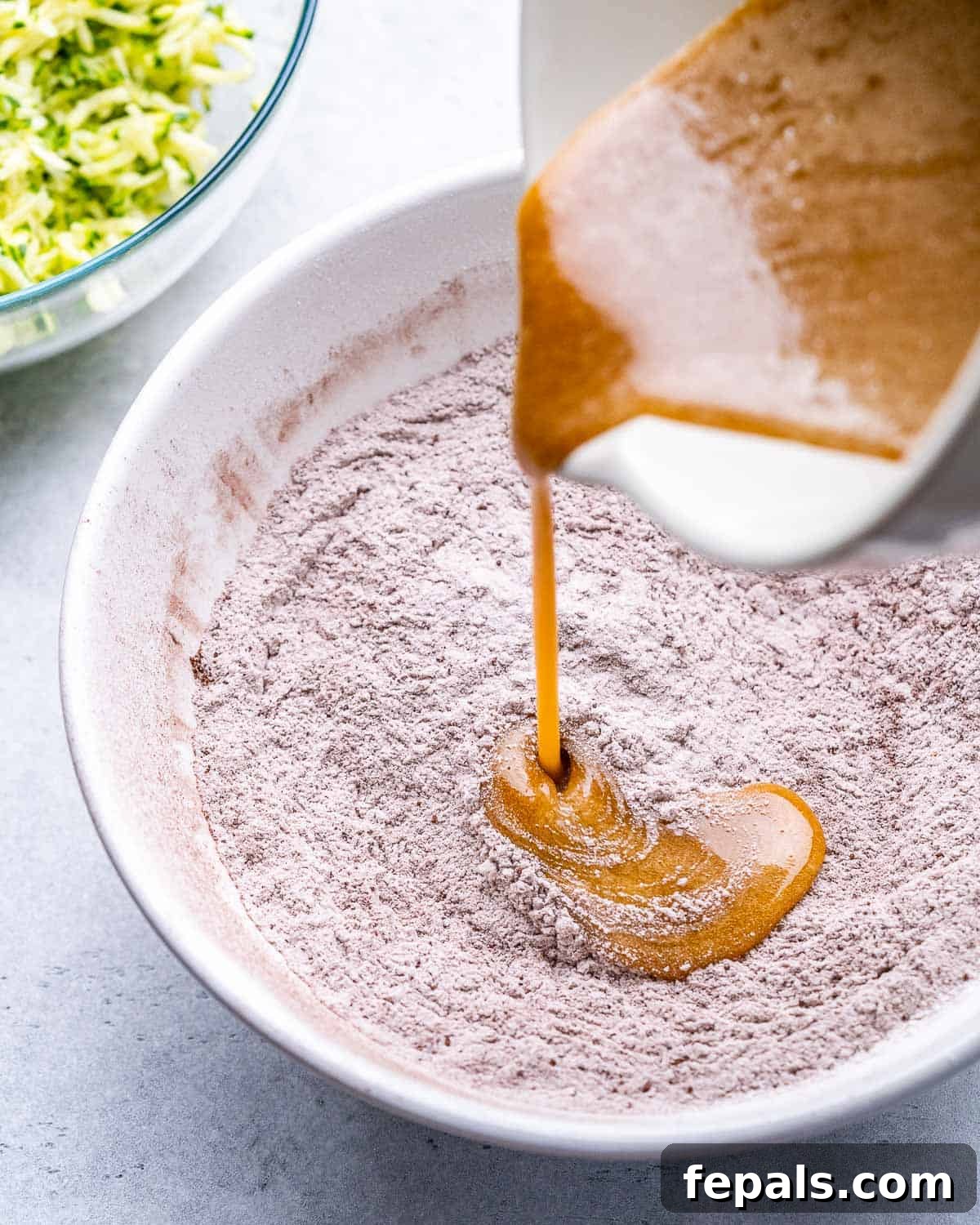 egg and oil liquid mixture being poured over the dry flour mixture