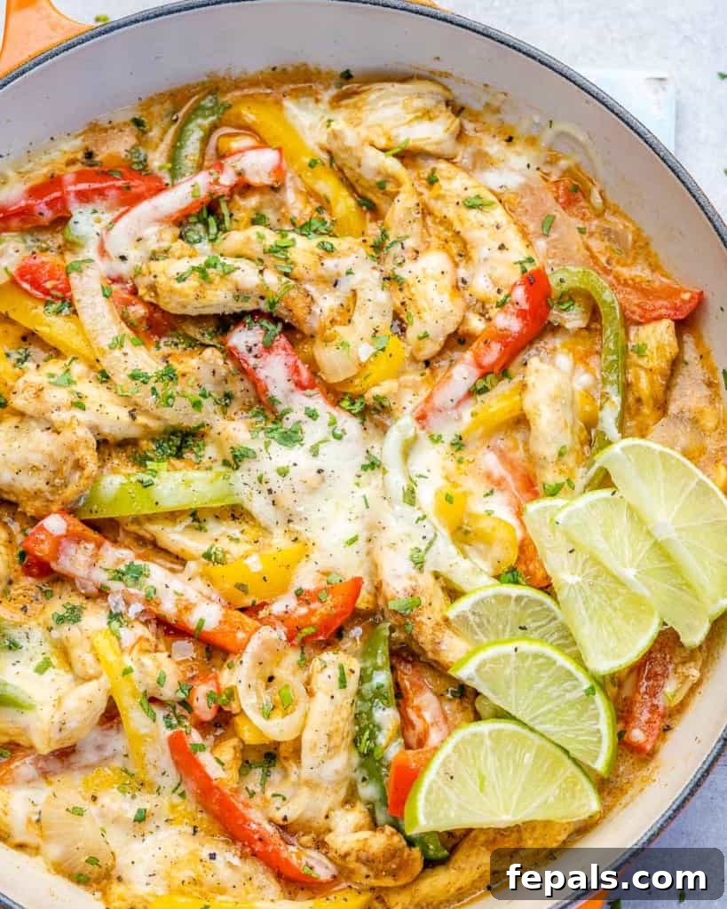 Dreamy Creamy Chicken Fajita Skillet 11 Creamy chicken fajitas in an orange skillet, perfectly cooked and garnished with lime wedges, ready for a delicious meal.