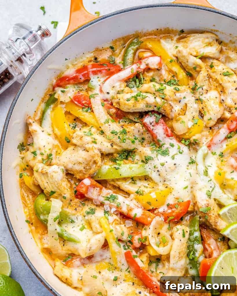 Dreamy Creamy Chicken Fajita Skillet 3 Close-up view of creamy chicken fajitas sizzling in a skillet, showcasing the melted cheese and tender ingredients.