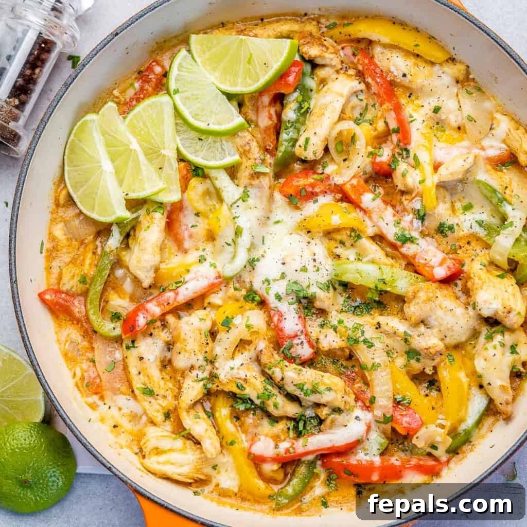 Dreamy Creamy Chicken Fajita Skillet 4 An inviting top view of creamy chicken fajitas generously topped with melted cheese in a vibrant orange skillet, garnished with fresh cilantro.