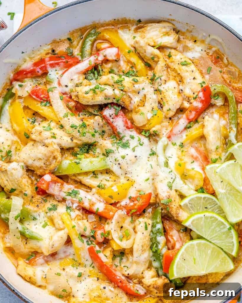 Dreamy Creamy Chicken Fajita Skillet 9 A close-up of cheesy chicken fajitas in a skillet, adorned with melted cheese and fresh lime wedges, ready to be enjoyed.