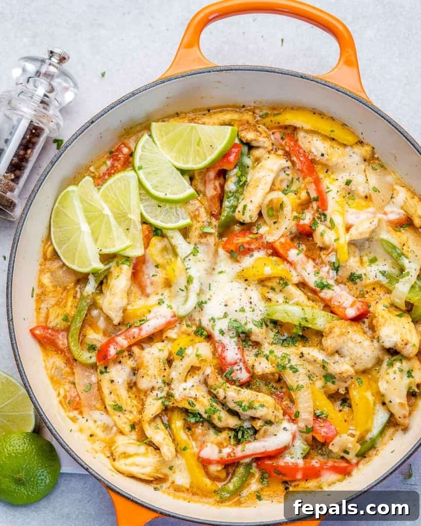 Dreamy Creamy Chicken Fajita Skillet 10 A vibrant orange skillet filled with creamy chicken fajitas, beautifully garnished with fresh lime wedges.