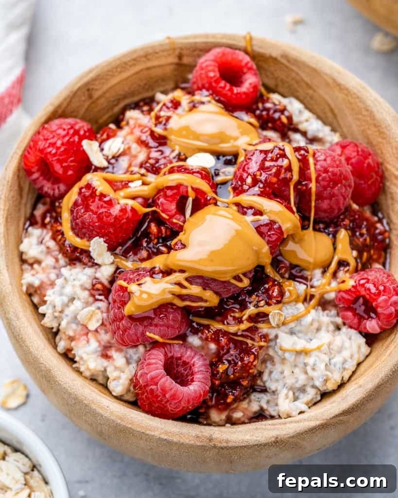Dreamy PB&J Overnight Oats 2 top view overnight oatmeal in a tan bowl topped with raspberry and peanut butter drizzle, a healthy and quick breakfast