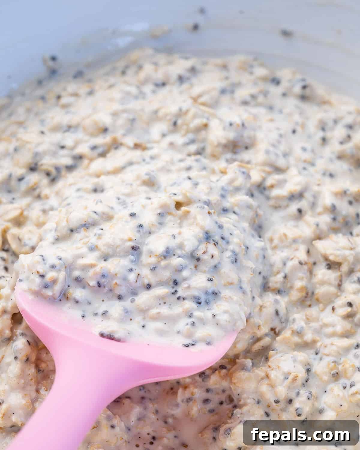 Dreamy PB&J Overnight Oats 6 thickened overnight oats in a bowl with pink spatula in it, after refrigerating overnight