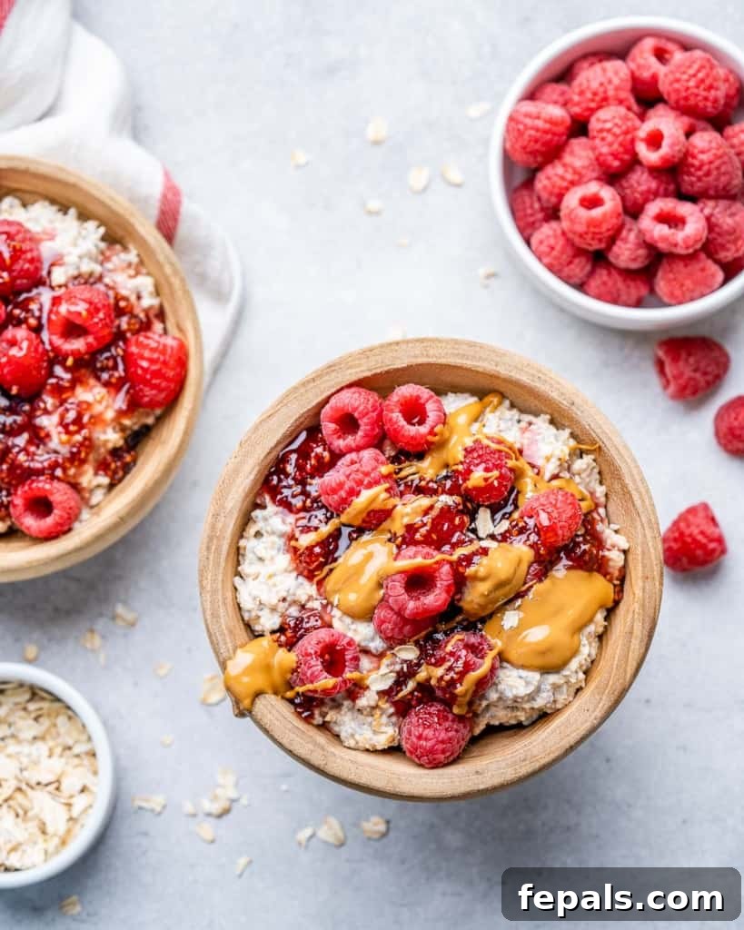 Dreamy PB&J Overnight Oats 7 top view of two bowls of overnight oatmeal topped with fresh raspberries and a generous peanut butter drizzle, ready to eat