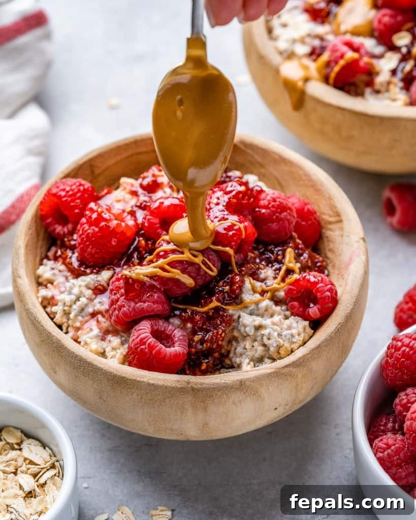Dreamy PB&J Overnight Oats 8 spoon drizzling peanut butter over a bowl of oatmeal topped with fresh raspberries, showcasing a delicious breakfast