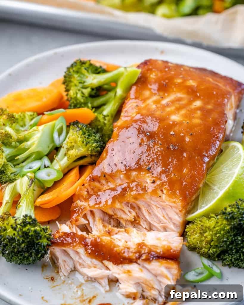 Umami Miso Salmon 3 flaky salmon filet on a plate with vibrant roasted broccoli and carrots on the side