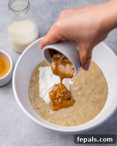 nut butter being poured over a bowl or mashed banana and yogurt