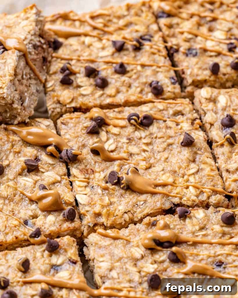 Close-up shot of baked chocolate chip oatmeal bars, some with a delightful drizzle of peanut butter on top.