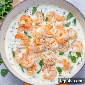 Top view shrimp in a creamy spinach sauce in an orange skillet
