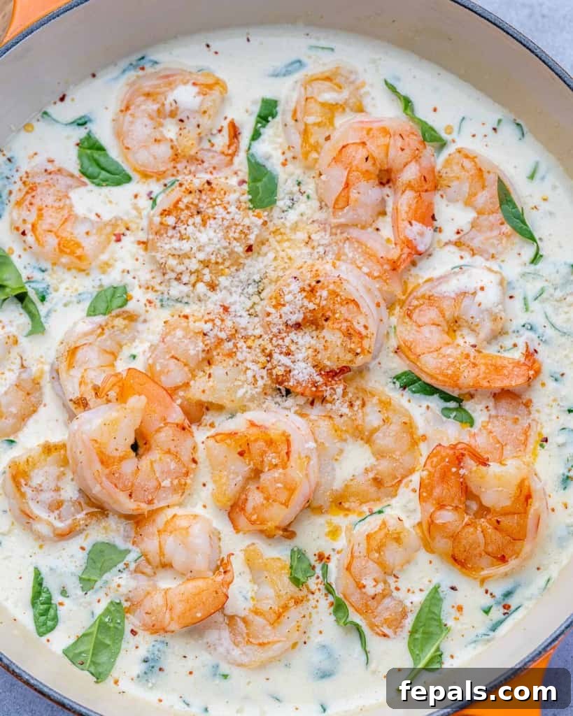 Close-up of a plate of creamy sauteed shrimp in a rich garlic parmesan sauce with visible spinach.