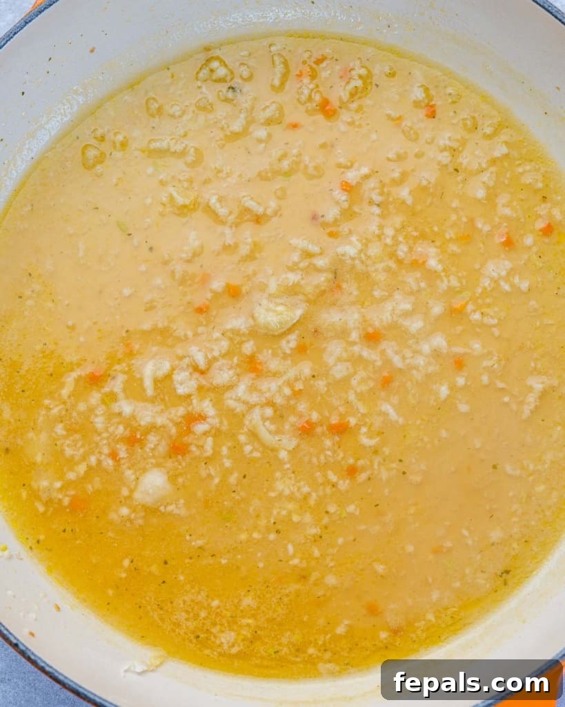 Creamy sauce simmering in a pan with spinach added, before the shrimp.