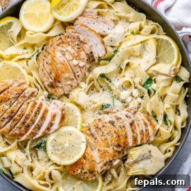 Top view of a serving of lemon garlic chicken pasta, garnished with lemon and fresh herbs.