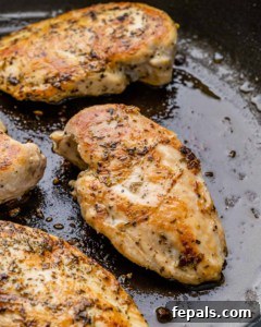 Cooked chicken breast in a black skillet, golden and ready for slicing.