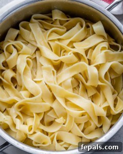 Fettuccine pasta boiling in a pot, ready to be drained.