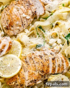 Close-up of lemon garlic chicken pasta being tossed in a skillet, showcasing the creamy sauce and fresh ingredients.